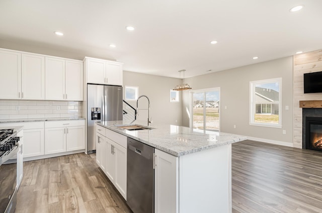 kitchen featuring a sink, open floor plan, light wood-style floors, a fireplace, and appliances with stainless steel finishes