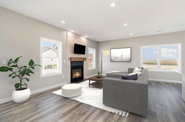 living room with a fireplace, wood finished floors, baseboards, and recessed lighting