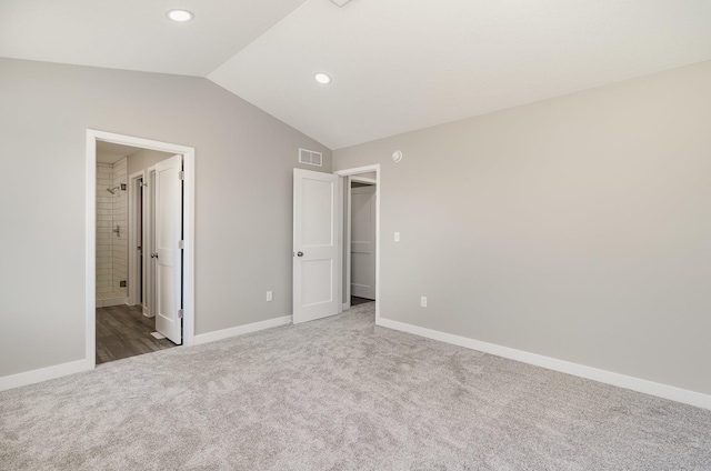 unfurnished bedroom with carpet floors, vaulted ceiling, visible vents, and baseboards