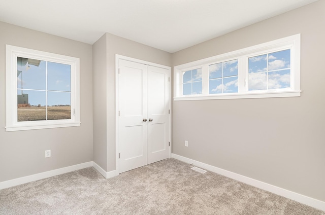 unfurnished bedroom featuring baseboards, a closet, and light colored carpet