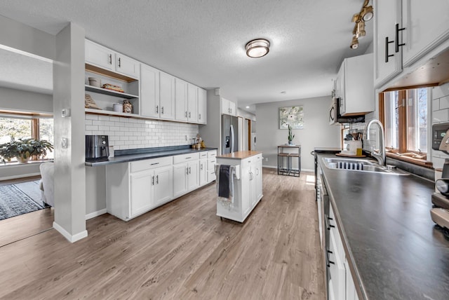 502 Seminole Ave, Osceola, WI 54020 - kitchen featuring tasteful backsplash, dark countertops, white cabinetry, open shelves, and light wood-style flooring