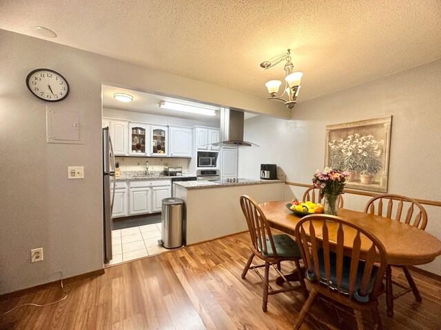 4120 Parklawn Ave Unit 134, Edina, MN 55435 - dining area featuring light wood-style flooring, a textured ceiling, a chandelier, and baseboards
