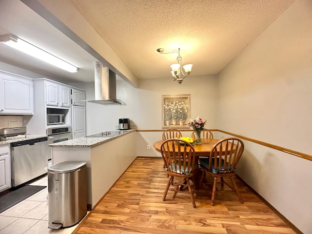 4120 Parklawn Ave Unit 134, Edina, MN 55435 - kitchen with a notable chandelier, a peninsula, a textured ceiling, wall chimney exhaust hood, and stainless steel appliances