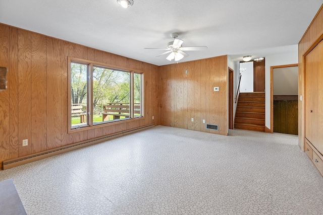 unfurnished room featuring wood walls, stairs, and ceiling fan