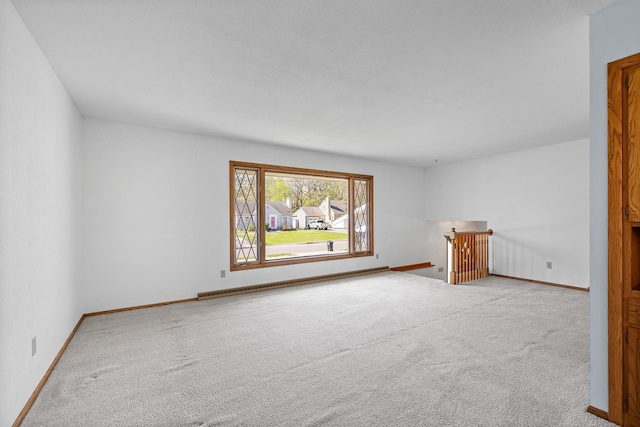 empty room featuring carpet floors, baseboards, and baseboard heating