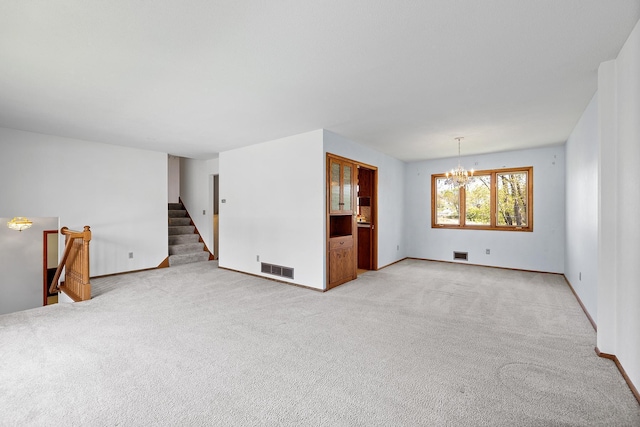 unfurnished living room featuring a chandelier, baseboards, light carpet, and stairs