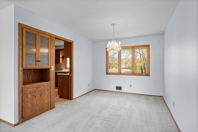 unfurnished dining area featuring light carpet, a chandelier, and baseboards