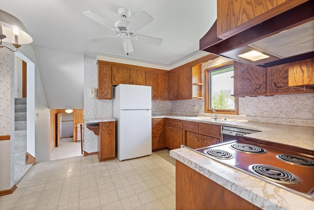 kitchen featuring freestanding refrigerator, a sink, range with electric stovetop, brown cabinetry, and wall chimney exhaust hood
