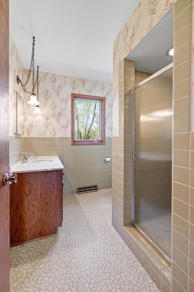 full bath with wallpapered walls, vanity, a shower stall, and tile walls
