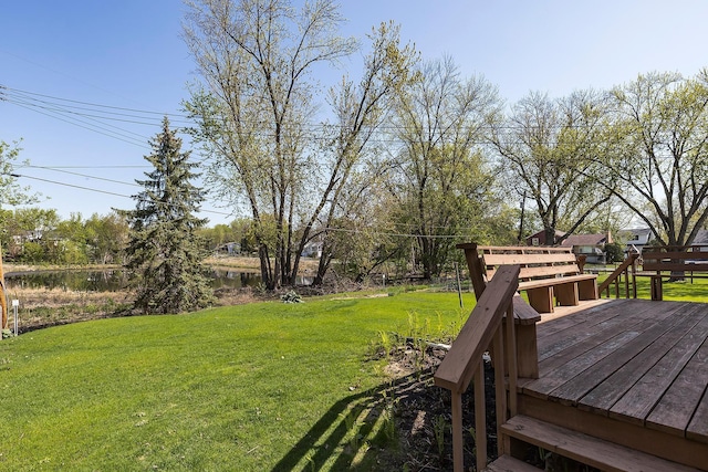 view of grassy yard featuring a deck with water view
