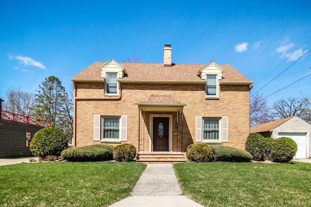 view of front of property with brick siding, a chimney, and a front yard