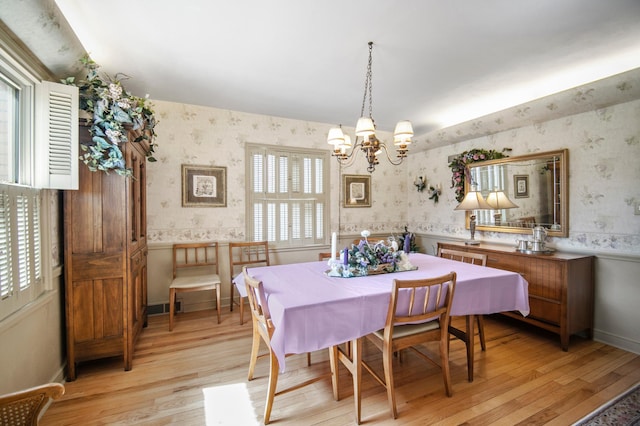 dining space with wallpapered walls, light wood-type flooring, and a chandelier