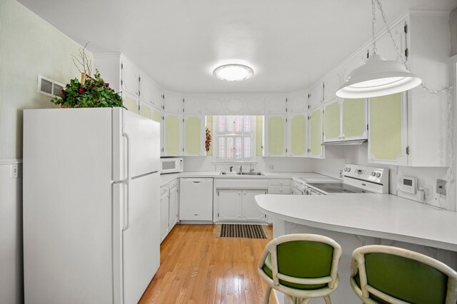 kitchen featuring white appliances, a peninsula, light wood-style floors, and light countertops