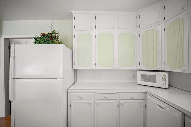 kitchen with white appliances, light countertops, and white cabinets