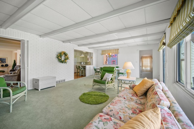 carpeted living room featuring beamed ceiling and a chandelier