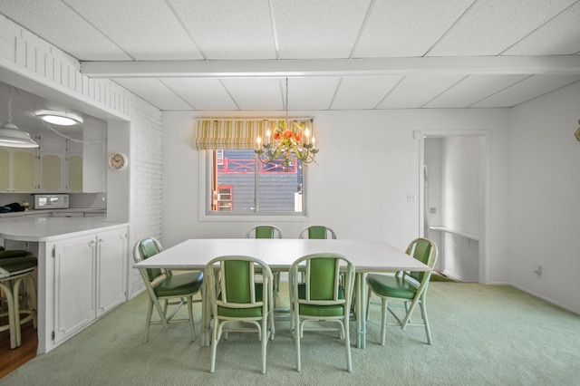 dining space featuring a chandelier, light carpet, and a drop ceiling