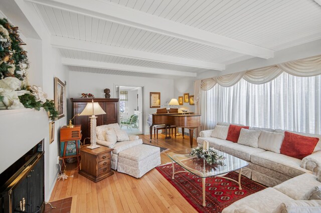 living area with beam ceiling, plenty of natural light, and light wood-type flooring