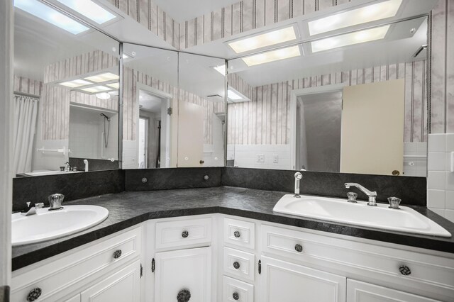 bathroom with wallpapered walls, double vanity, and a shower with curtain