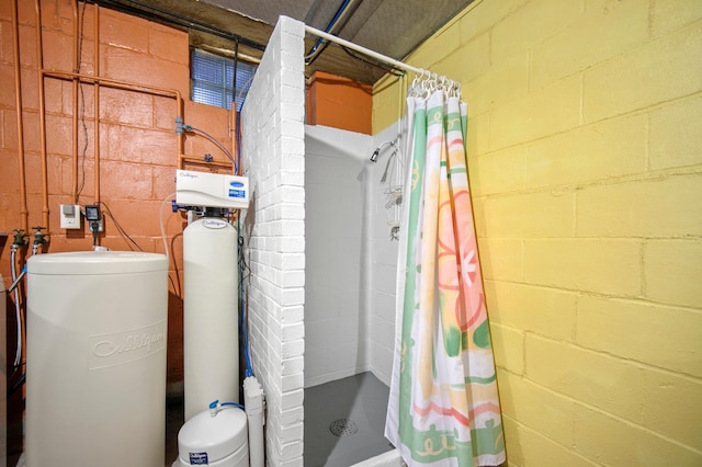 bathroom with concrete block wall, a shower stall, and toilet