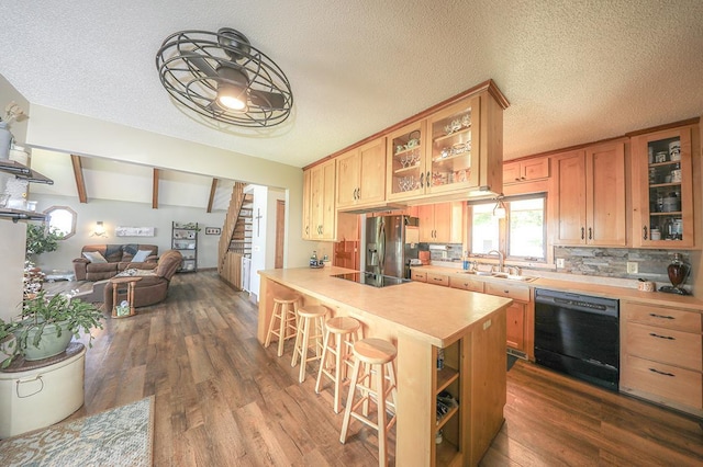 kitchen with open floor plan, light countertops, black appliances, a kitchen bar, and a sink