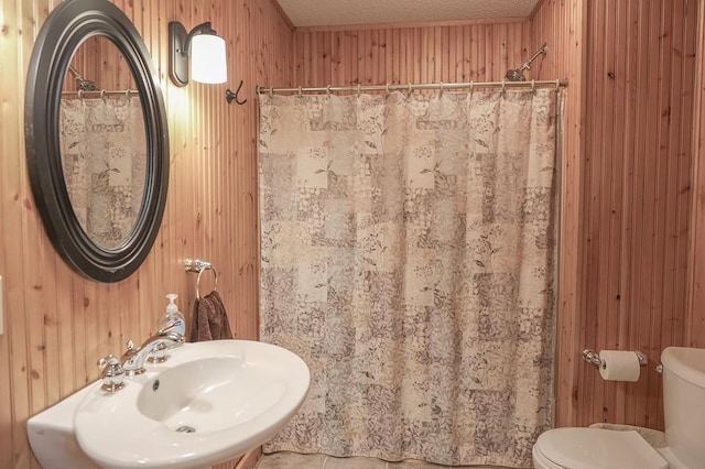 full bath featuring toilet, wood walls, and a sink