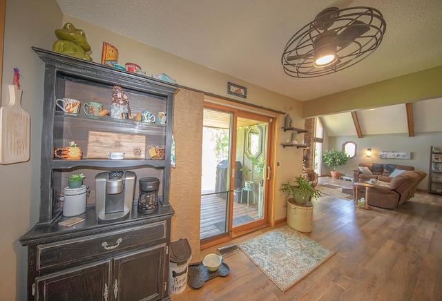 doorway featuring visible vents, a textured ceiling, wood finished floors, and lofted ceiling with beams