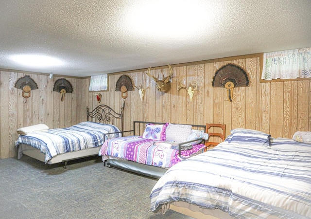 bedroom with wood walls, carpet flooring, and a textured ceiling
