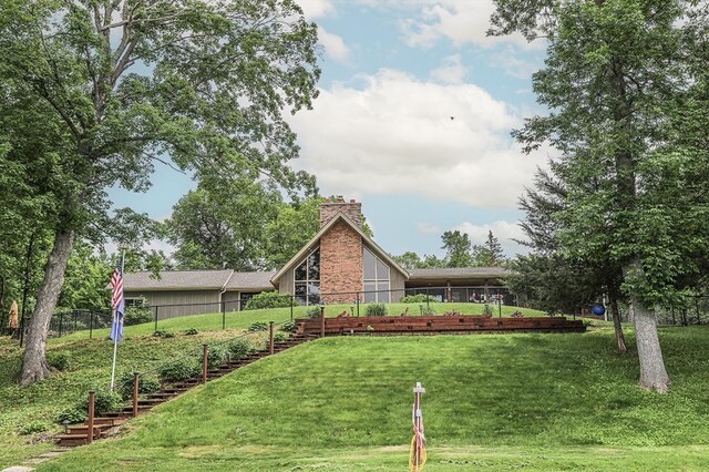 view of front facade with a chimney, fence, and a front lawn