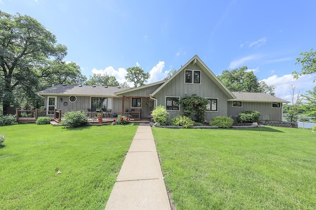 view of front of property with a front lawn, a shingled roof, and a deck