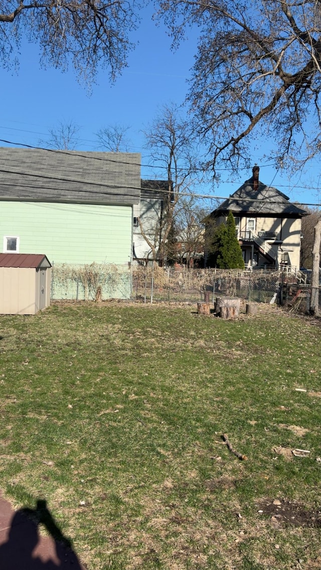 view of yard featuring a storage unit, fence, and an outdoor structure