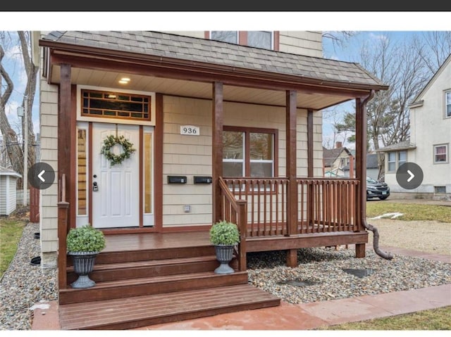 property entrance featuring a shingled roof and covered porch