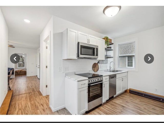 kitchen featuring light wood-style flooring, a sink, stainless steel appliances, light countertops, and decorative backsplash