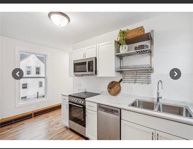 kitchen featuring a sink, open shelves, backsplash, white cabinets, and appliances with stainless steel finishes
