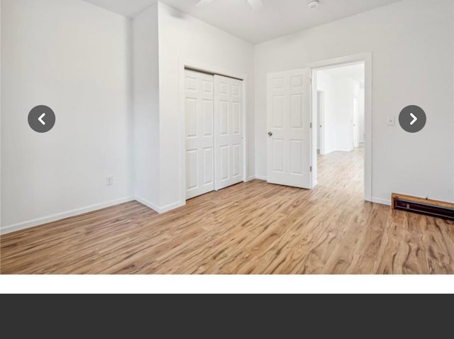 unfurnished bedroom with a closet, light wood-style floors, visible vents, and baseboards
