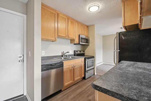 4110 Rahn Rd Unit 124, Eagan, MN 55122 - kitchen featuring appliances with stainless steel finishes, dark countertops, a textured ceiling, wood finished floors, and light brown cabinetry