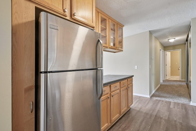 4110 Rahn Rd Unit 124, Eagan, MN 55122 - kitchen featuring freestanding refrigerator, dark wood-style floors, dark countertops, glass insert cabinets, and a textured ceiling