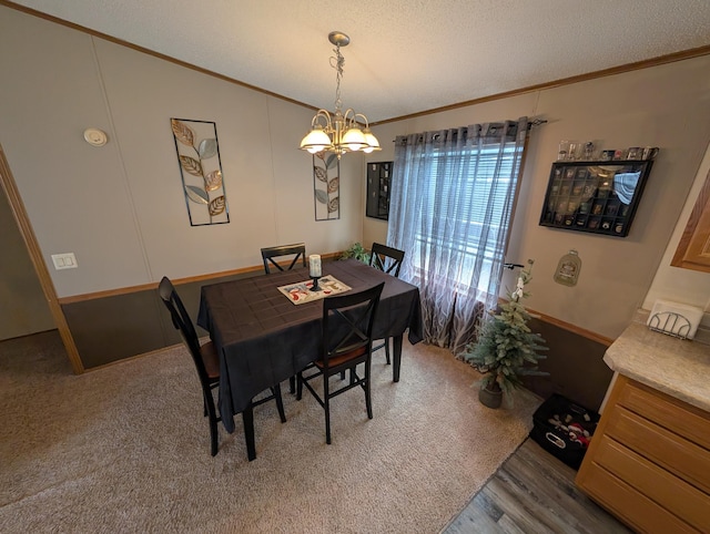 dining space featuring a textured ceiling, wood finished floors, an inviting chandelier, and ornamental molding