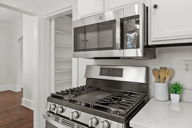 4001 Sheridan Ave S, Minneapolis, MN 55410 - kitchen with stainless steel appliances, ornamental molding, white cabinetry, light stone counters, and dark wood-style flooring