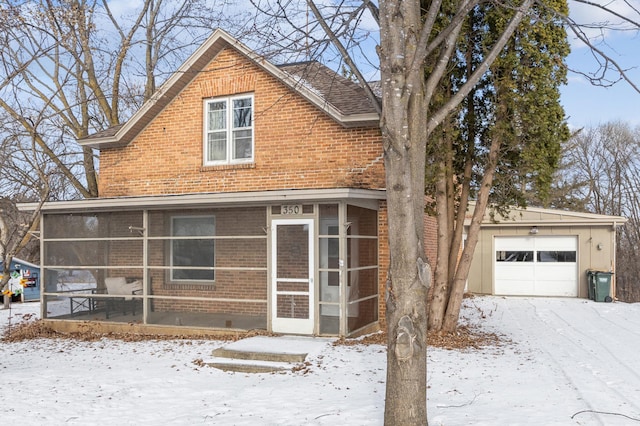 view of front of home with a sunroom, a garage, an outdoor structure, and brick siding