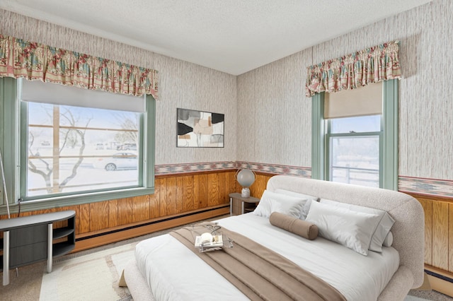 carpeted bedroom featuring multiple windows, baseboard heating, and wallpapered walls