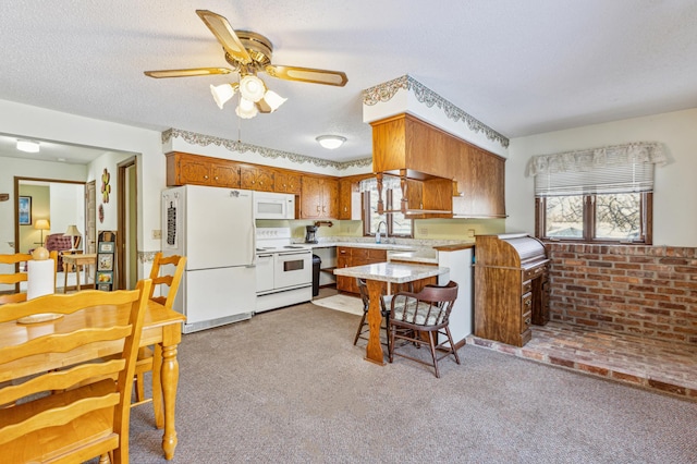 kitchen with a healthy amount of sunlight, light colored carpet, light countertops, and white appliances