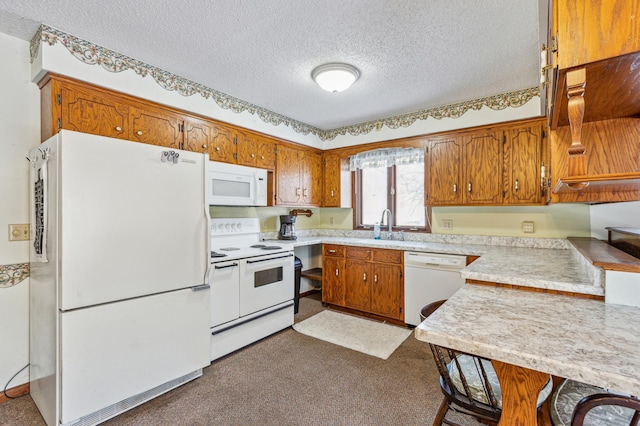 kitchen with white appliances, brown cabinetry, a textured ceiling, light countertops, and a sink
