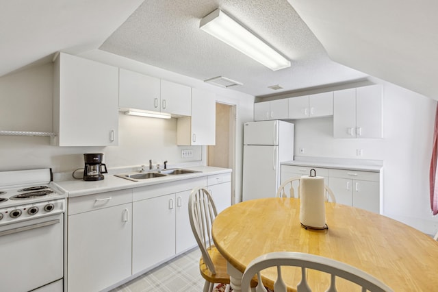 kitchen featuring white appliances, light countertops, white cabinetry, a textured ceiling, and a sink
