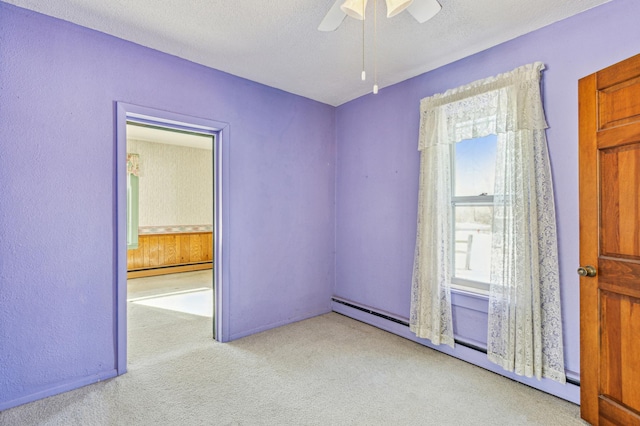 spare room featuring carpet flooring, baseboard heating, a textured ceiling, and a ceiling fan