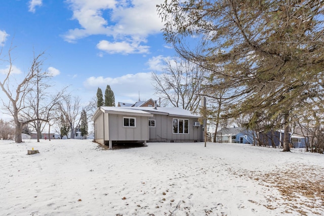 snow covered back of property featuring board and batten siding