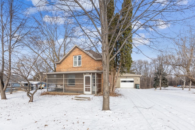 view of front facade featuring a sunroom, a detached garage, and brick siding