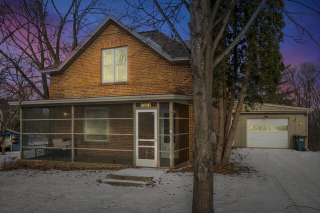 exterior space featuring a sunroom, a garage, aphalt driveway, and brick siding