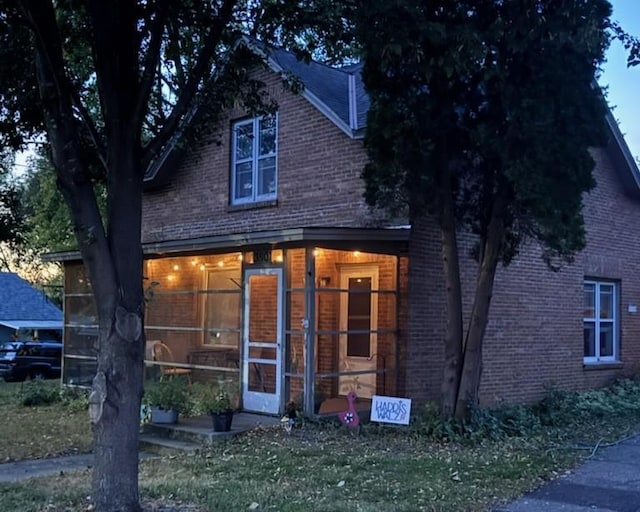 view of front of property featuring brick siding and a sunroom