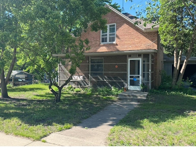 bungalow-style home with brick siding, a sunroom, and a front lawn