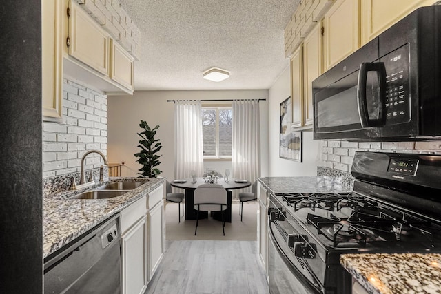 kitchen with black appliances, a sink, light wood-style floors, light stone counters, and a textured ceiling